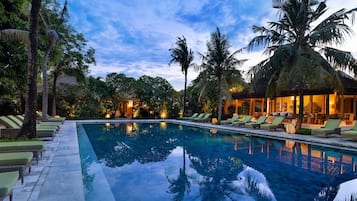 Una piscina al aire libre, sombrillas, sillones reclinables de piscina