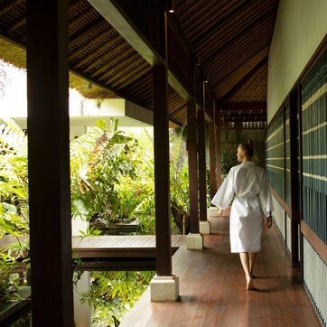A corridor with a wooden ceiling and a person walking away from the camera.