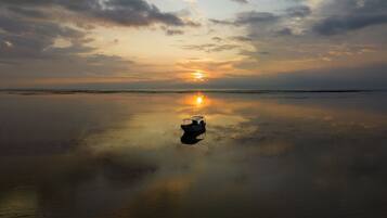 Una playa con mar tranquilo y un atardecer.