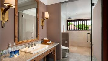Un baño moderno con lavamanos de mármol, un espejo grande y cabina de ducha con mampara de vidrio.