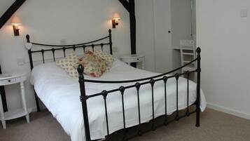 A bedroom with a black metal bed frame, white bedding, and two bedside tables.