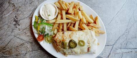 A plate with a wrap, fries, and a side salad.