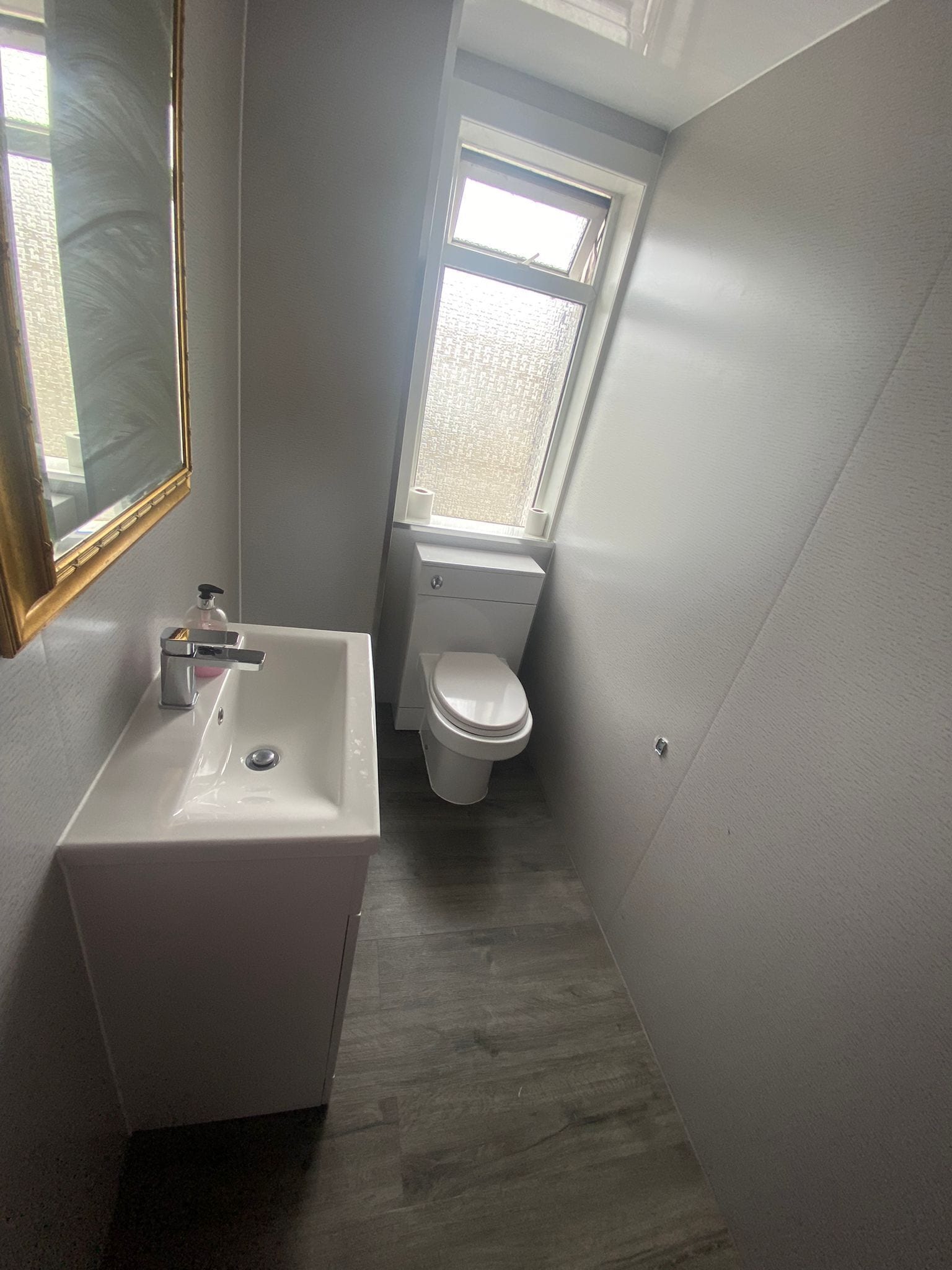 Un baño pequeño con un lavamanos blanco, un inodoro y una ventana.