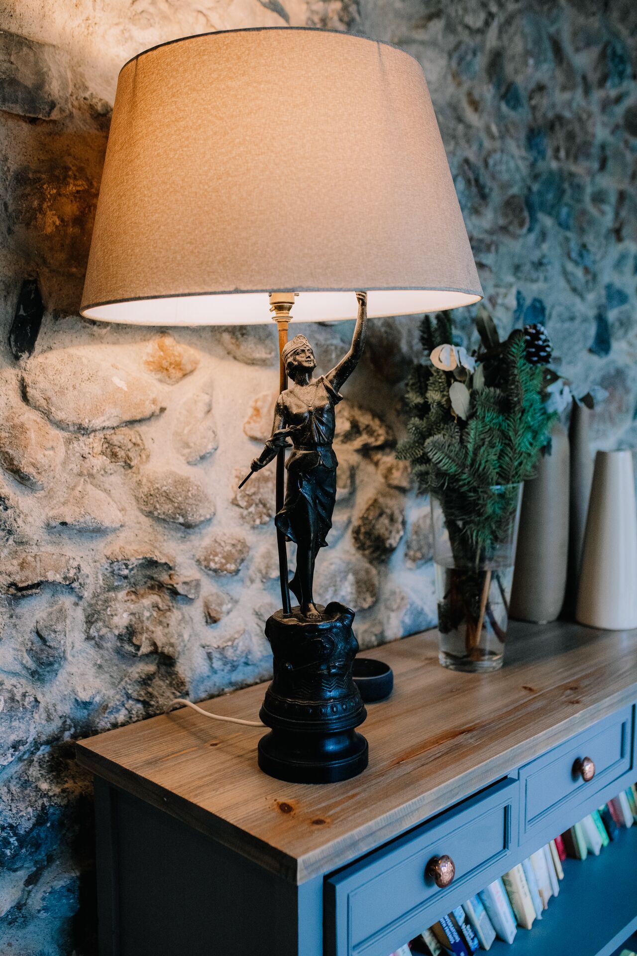 Een standbeeld op een houten tafel, met een lamp erboven.