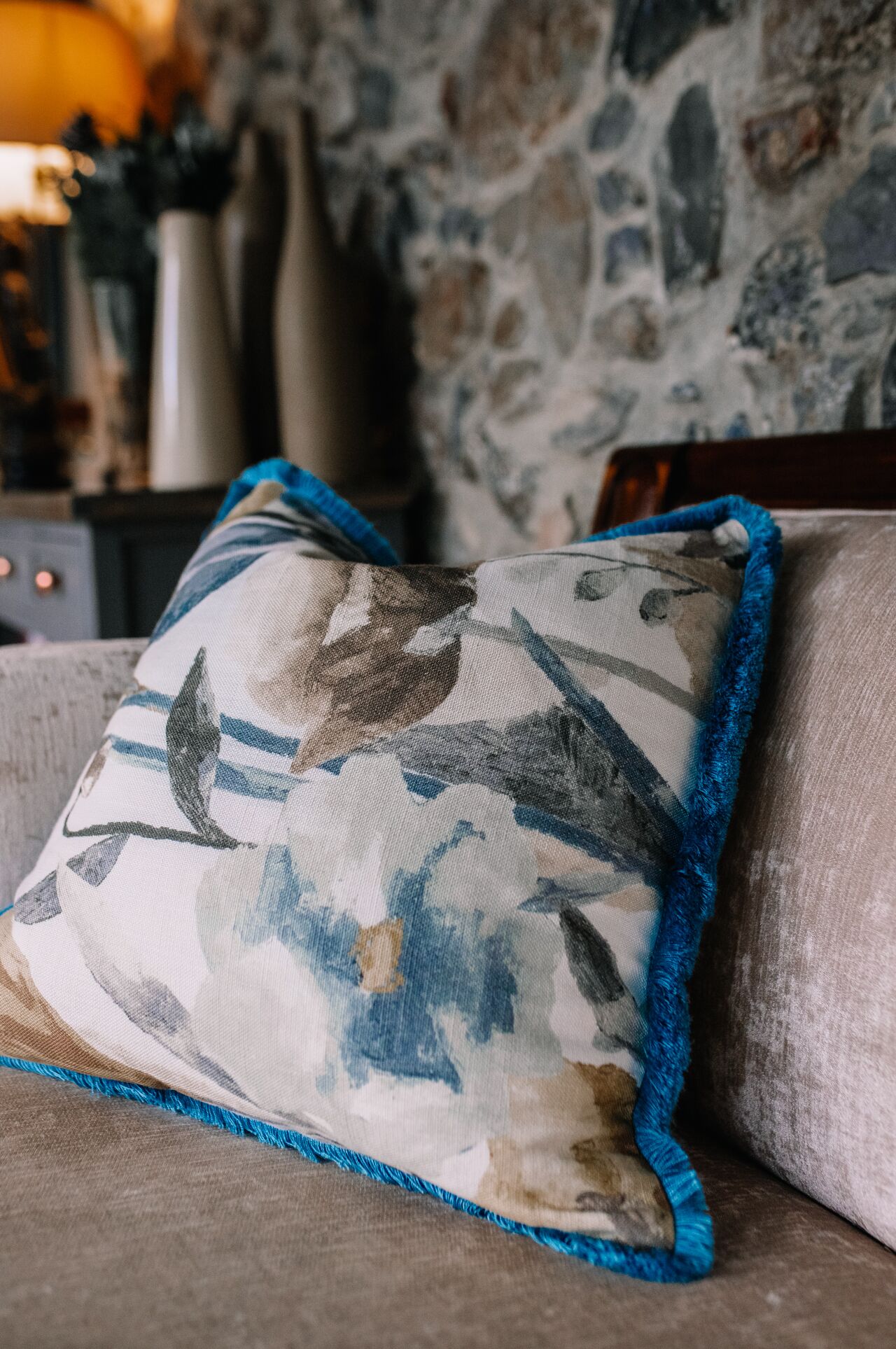 A cushion with a blue fringe on a couch.