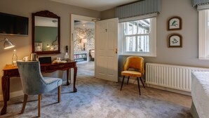 Un dormitorio con cama, escritorio, silla, espejo y ventana.