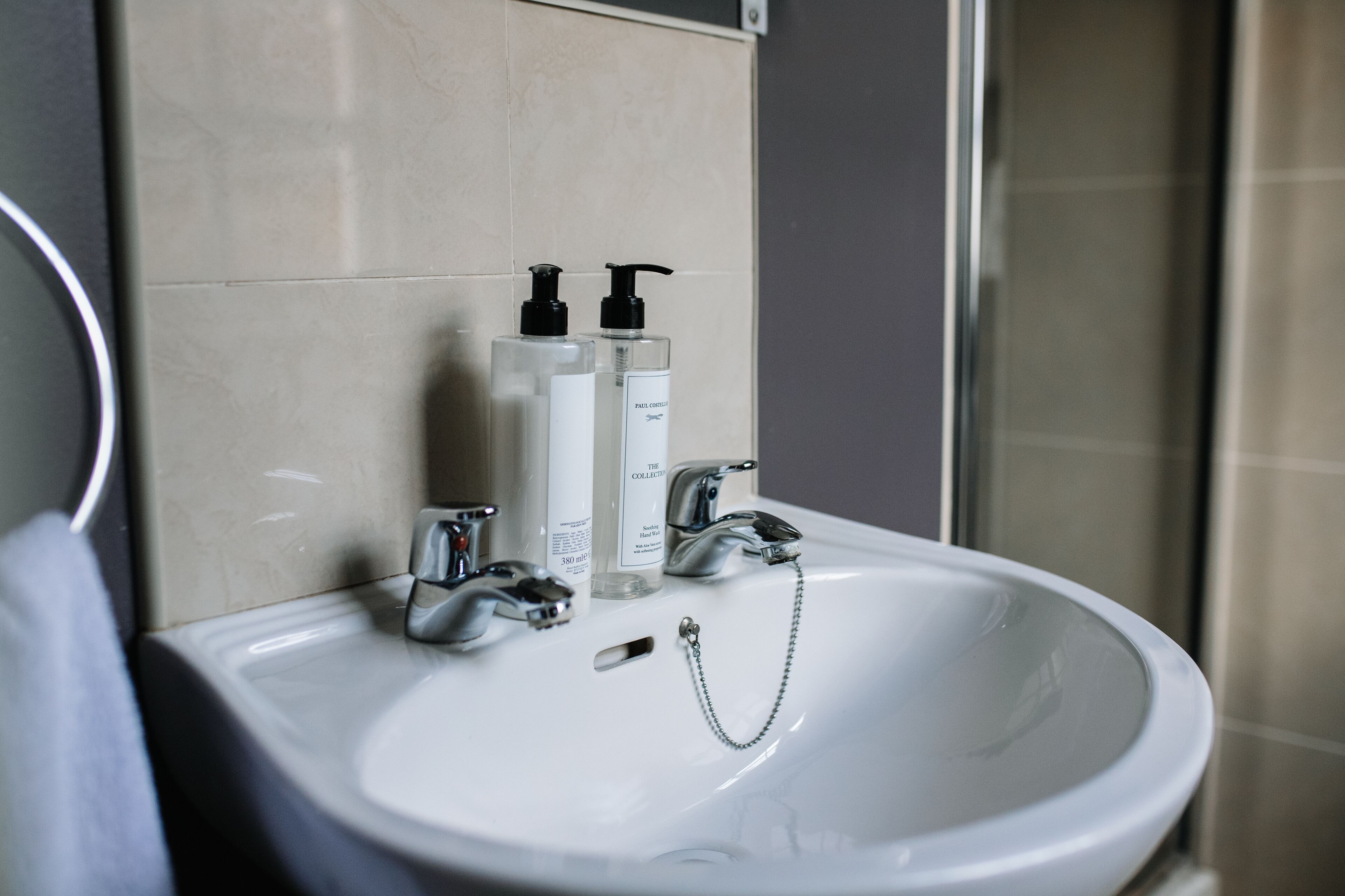 Un lavabo de salle de bain avec deux flacons de savon liquide et un robinet.