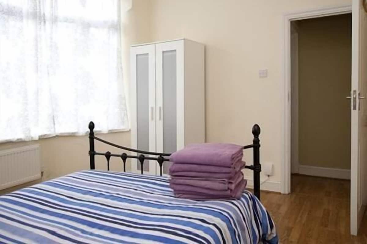 A bedroom with a bed, a wardrobe, and a door leading to another room.