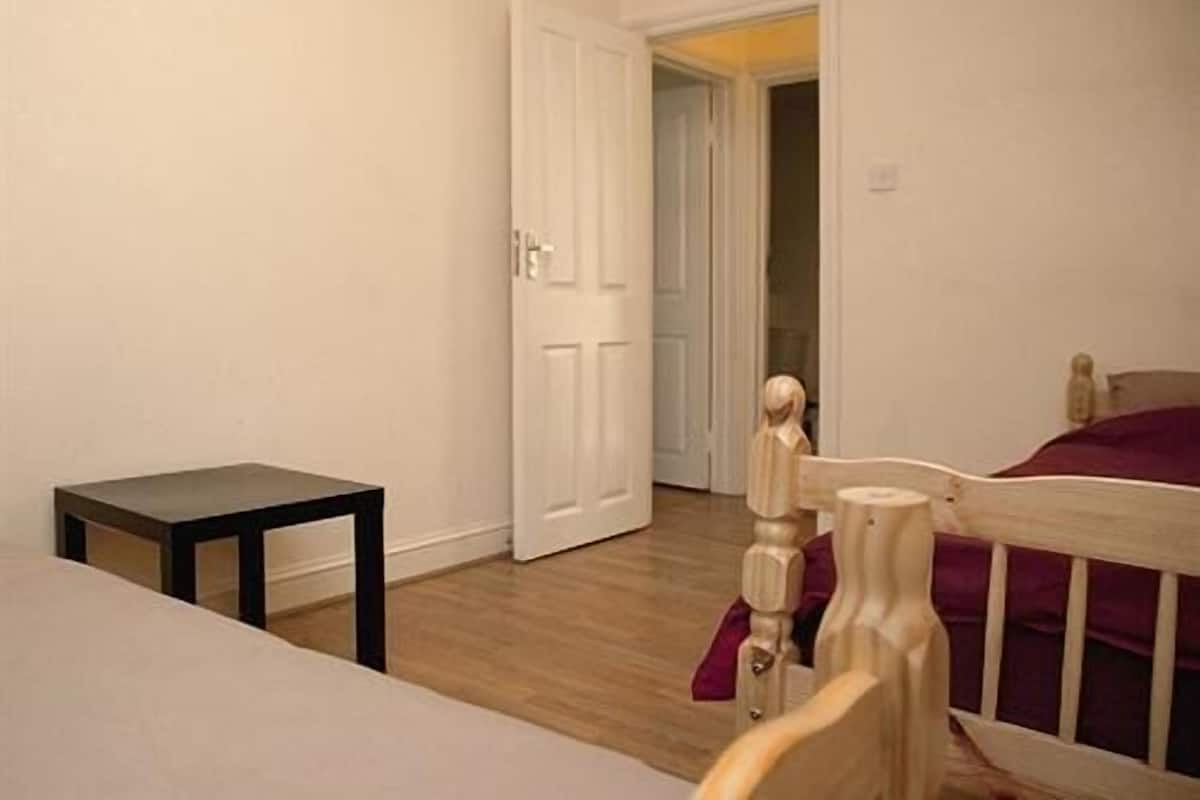 A bedroom with a wooden bed, a small table, and a white door leading to another room.