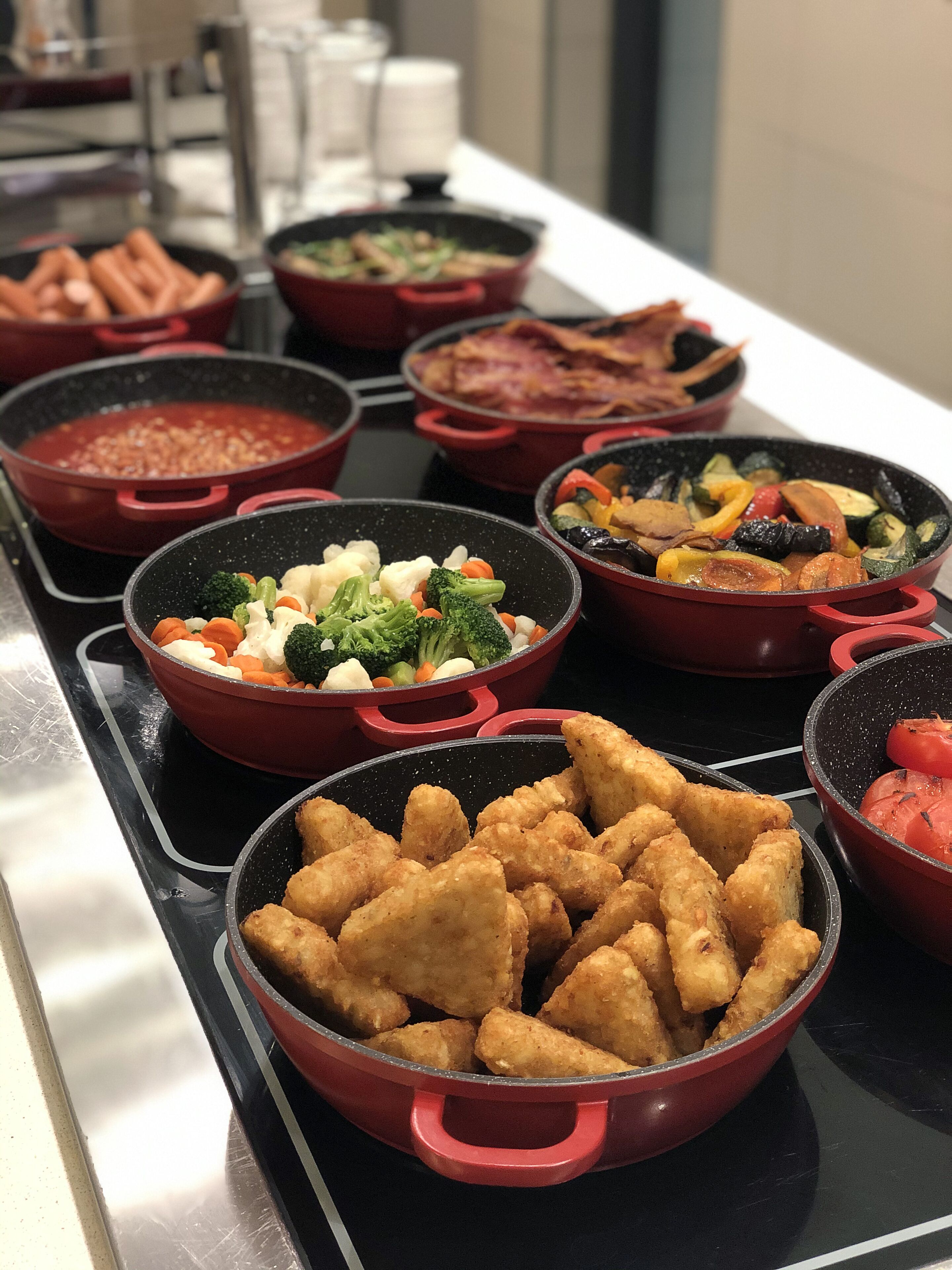 Buffet com diversos pratos, incluindo vegetais, carne e frituras.