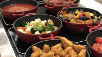 Buffet com diversos pratos, incluindo vegetais, carne e frituras.