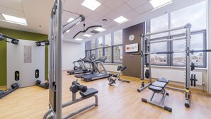 A gym with treadmills, weight machines, and a large window with a city view.