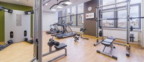A gym with treadmills, weight machines, and a large window with a city view.