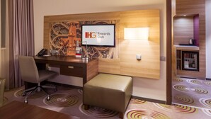A hotel room with a desk, chair, and a television displaying "IHG Rewards Club".