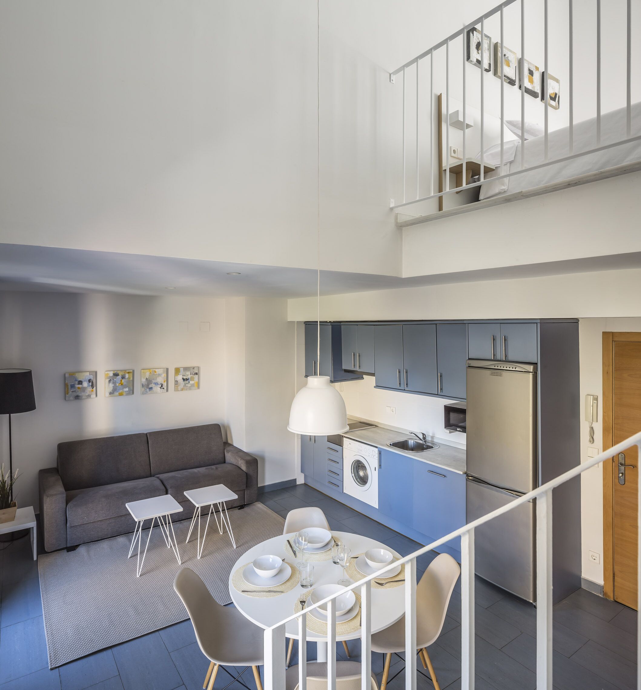 Un apartamento moderno con comedor, cocina y una escalera que sube a un nivel superior.