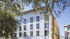 Un edificio de varios pisos con fachada blanca, varias ventanas y entrada a nivel de calle.