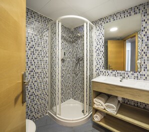 A bathroom with a glass-enclosed shower, a sink with a mirror, and a tiled wall. - Mon Suites Carmen (Valencia)