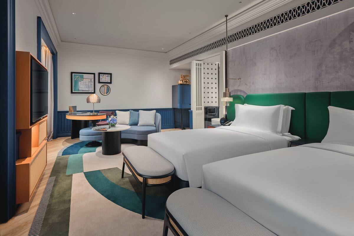 Ein modernes Hotelzimmer mit zwei Betten, einer Couch, einem kleinen Tisch und einem Fernseher.