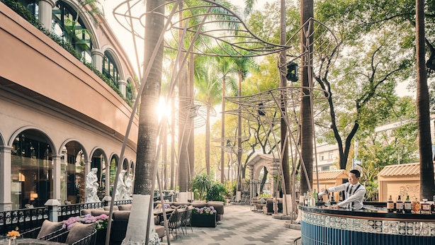 Un espacio al aire libre con mesas, sillas, una barra y un árbol decorativo.