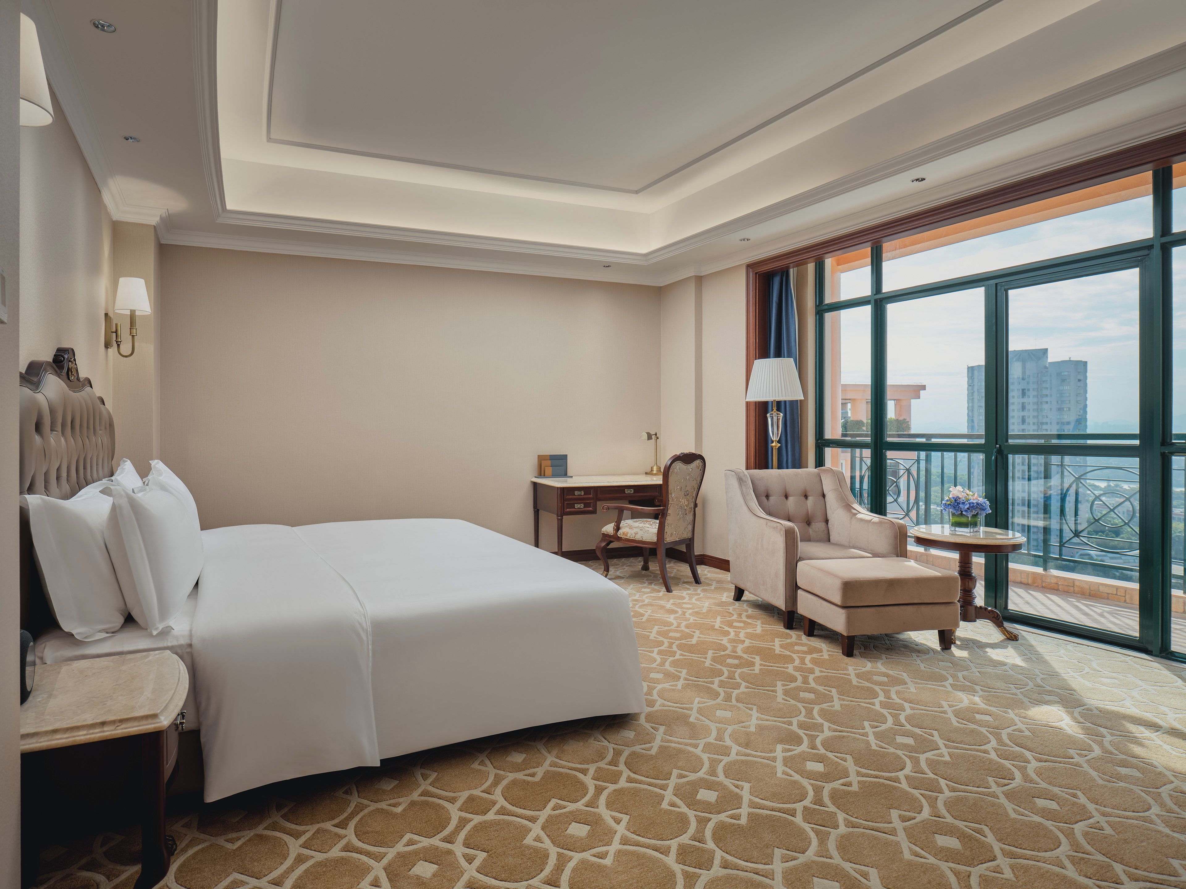 A hotel room with a large bed, a desk, a chair, and a balcony with a view.