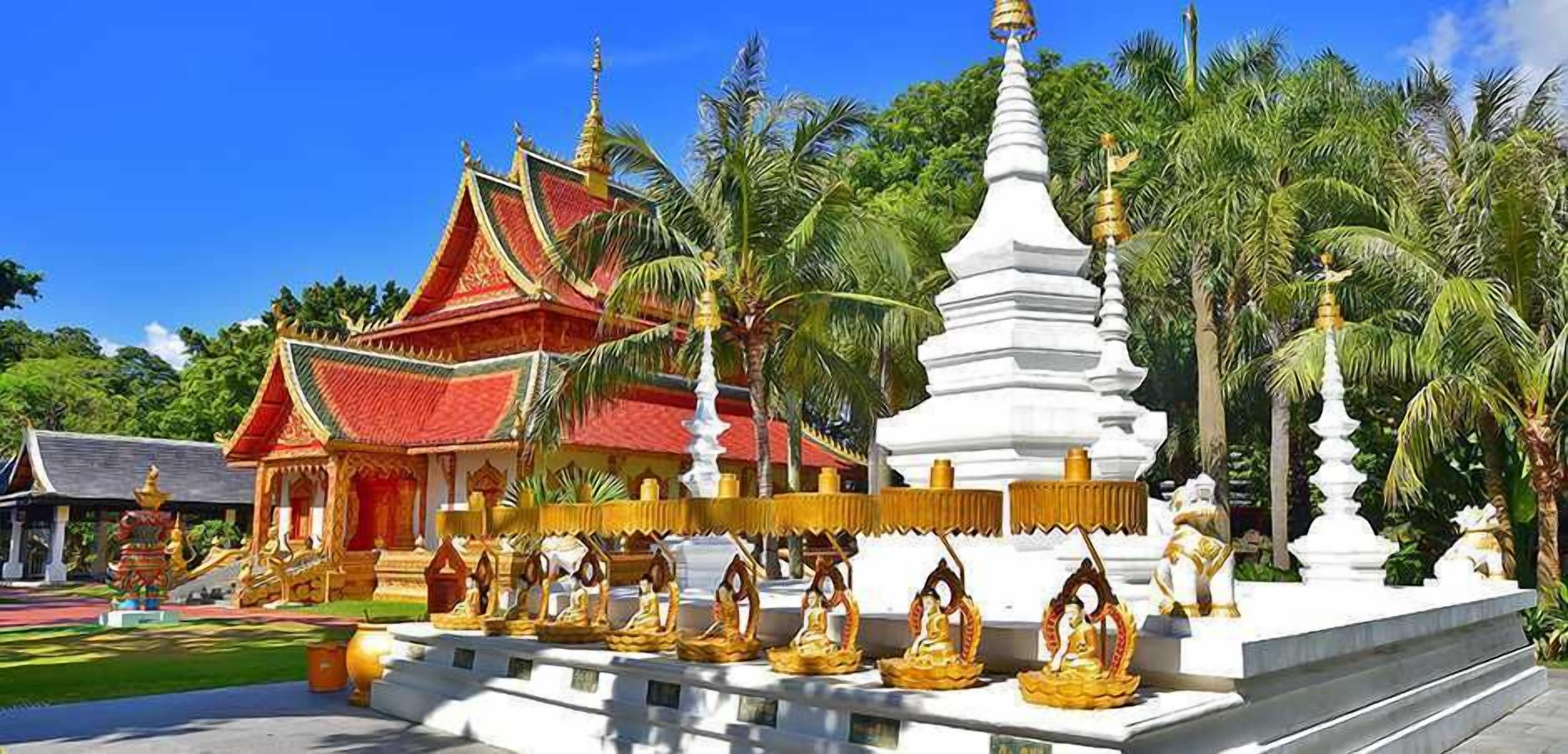 A traditional temple with a red roof, white spire, and golden statues.