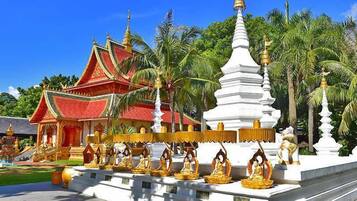 A traditional temple with a red roof, white spire, and golden statues.