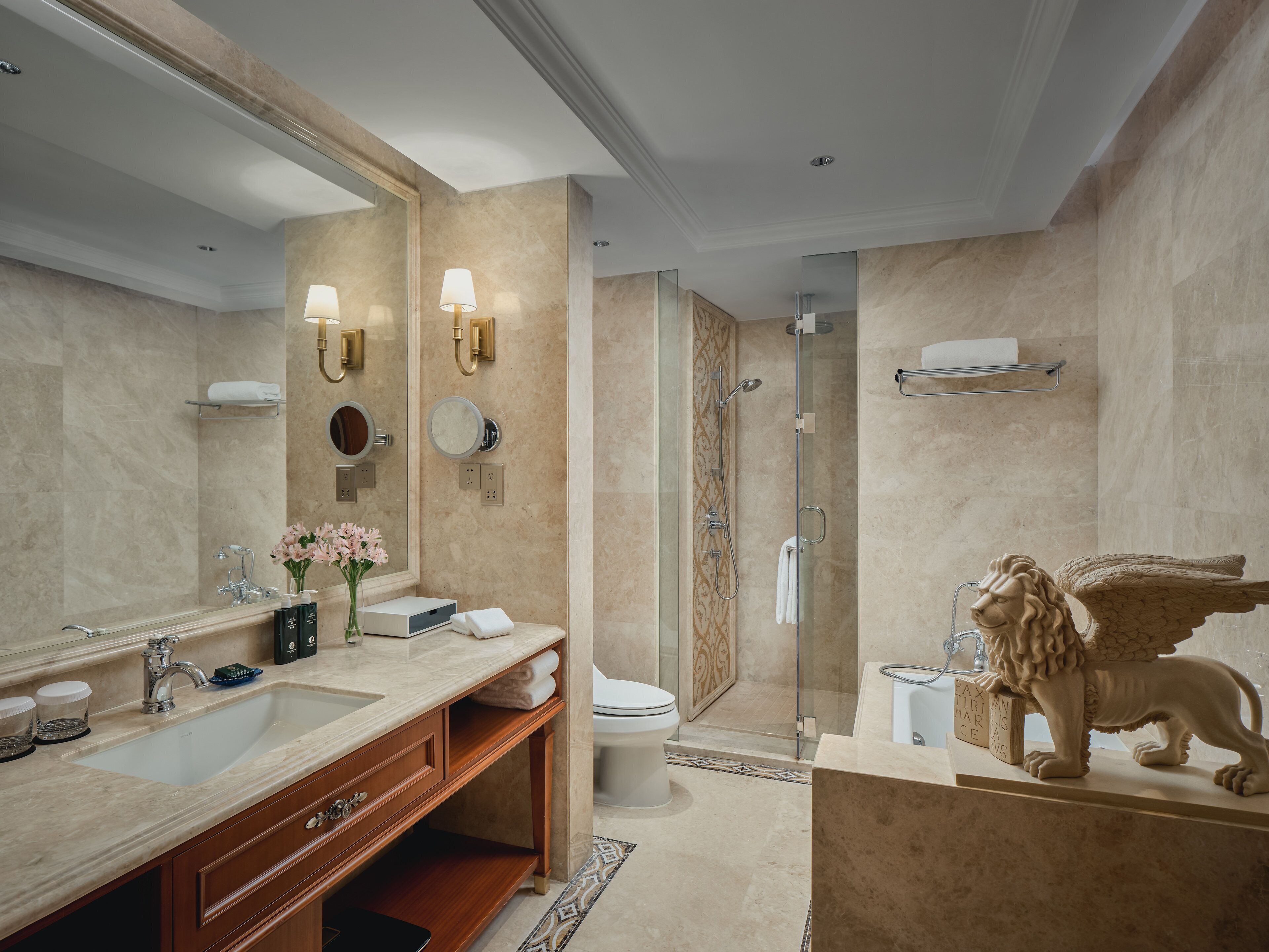 Un baño moderno con lavabo de mármol, tocador y ducha con mampara de vidrio.