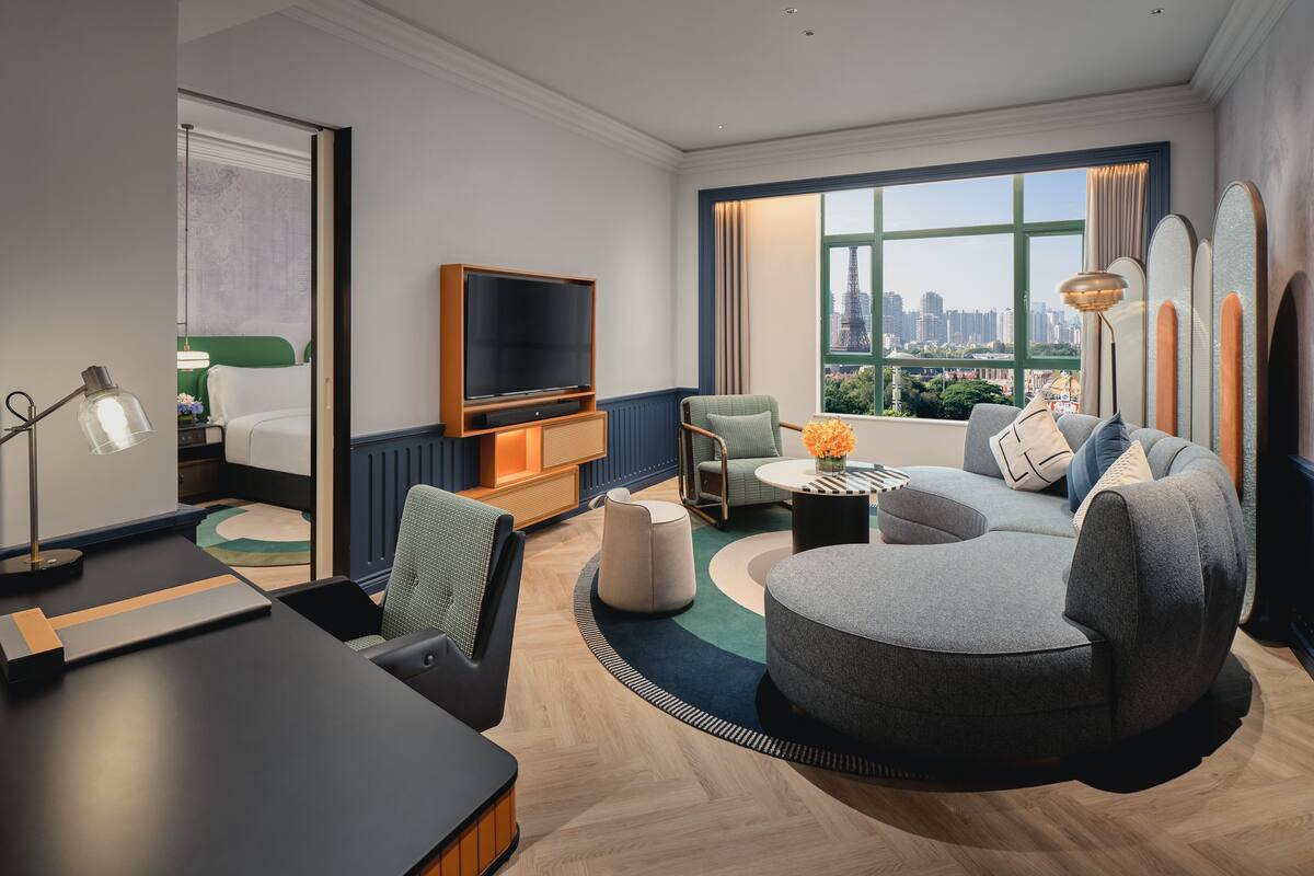 Ein modernes Wohnzimmer mit einer Couch, einem Fernseher und Blick auf die Stadtlandschaft.
