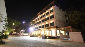 A multi-story hotel with a modern design, featuring a covered outdoor area with seating and potted plants. - Riverview Hotel (Ahmedabad)