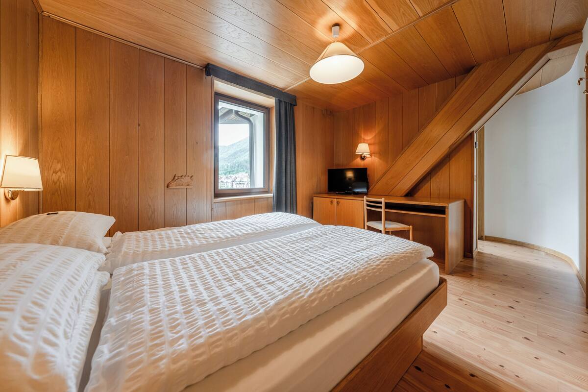 Een kamer met houten lambrisering, een bed, een bureau en een televisie.