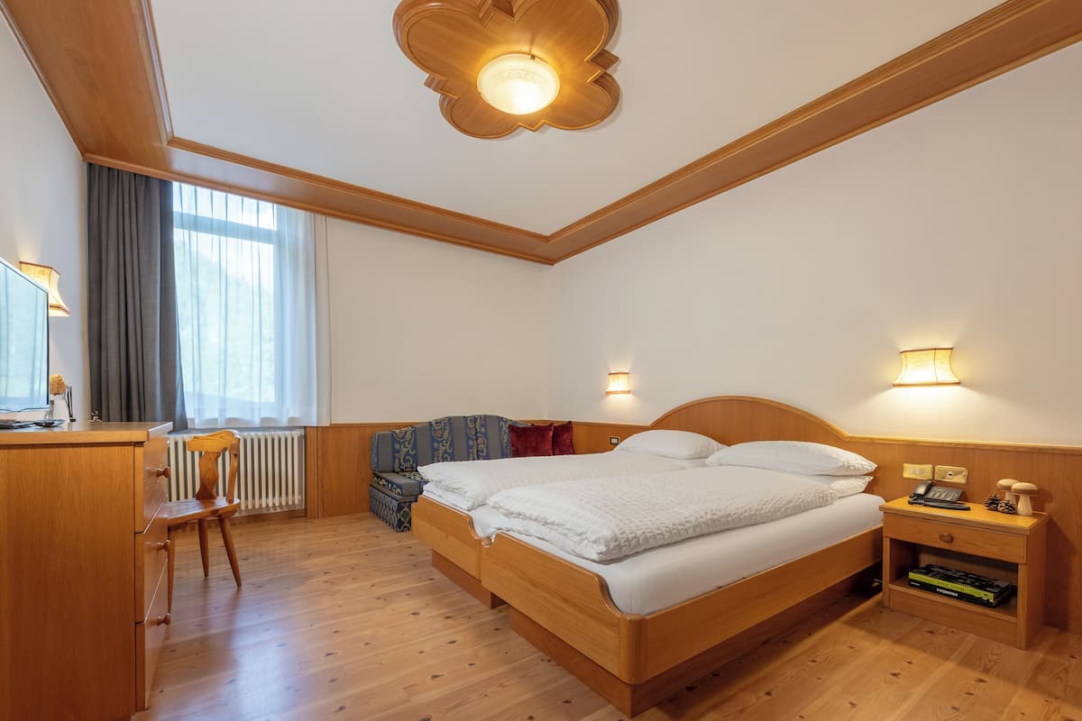 Een slaapkamer met een houten bed, nachtkastjes, een bureau en een stoel.
