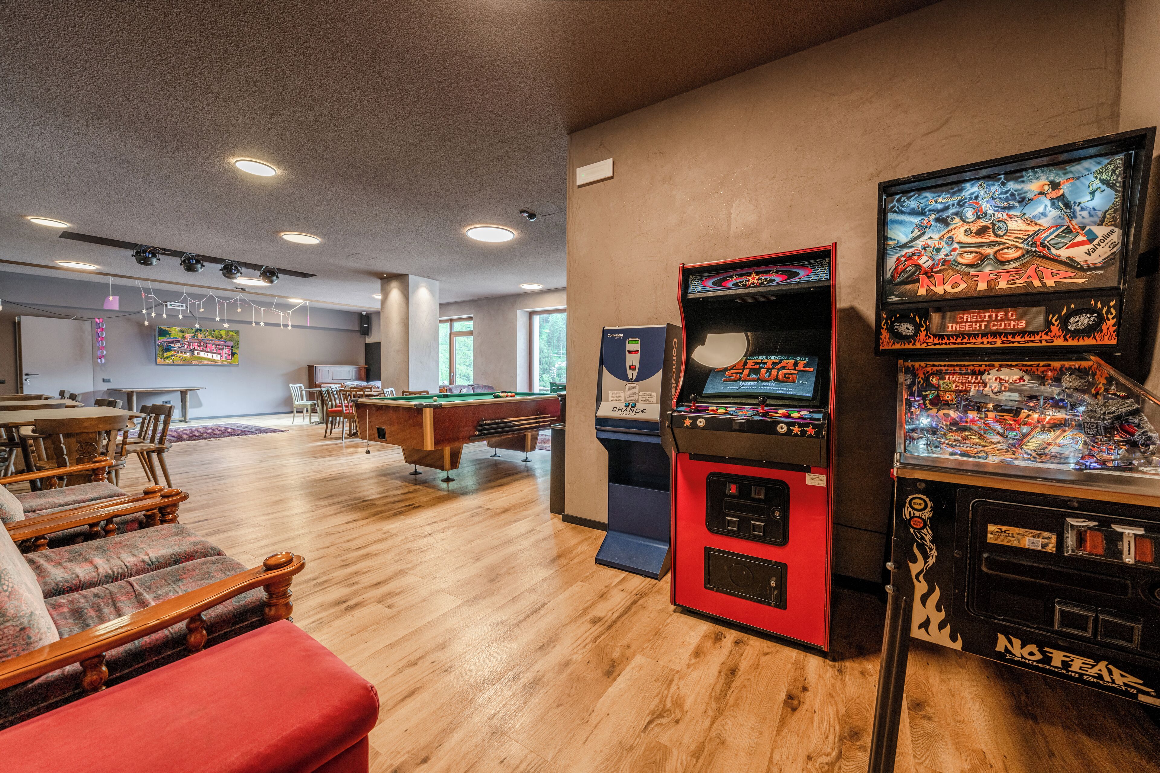 Una habitació amb billar, una màquina recreativa vermella i un futbolí.