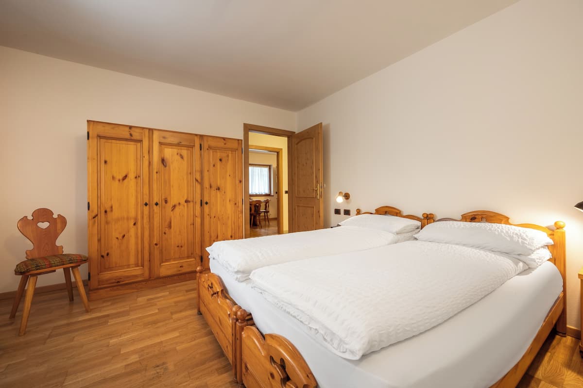 Een slaapkamer met een tweepersoonsbed, een houten garderobe en een stoel.