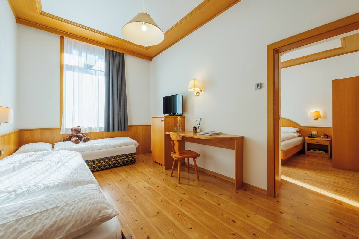 Een hotelkamer met twee bedden, een bureau, een televisie en een grote spiegel.