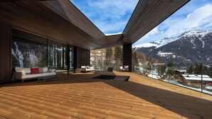 Ein modernes Interieur mit Holzboden, großen Fenstern und Blick auf schneebedeckte Berge.