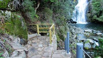 A stone staircase leading to a wooden viewing platform overlooking a waterfall.