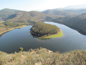 A lake surrounded by forested hills. - Apartamentos Rurales Azabal (Casar de Palomero)