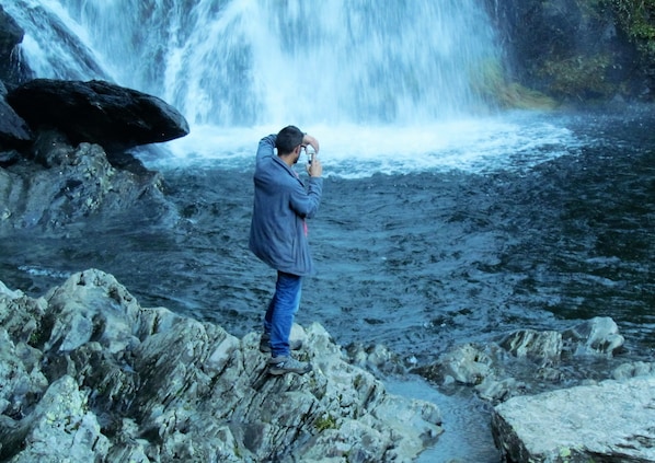A person taking a photo of a waterfall. - Apartamentos Rurales Azabal (Casar de Palomero)