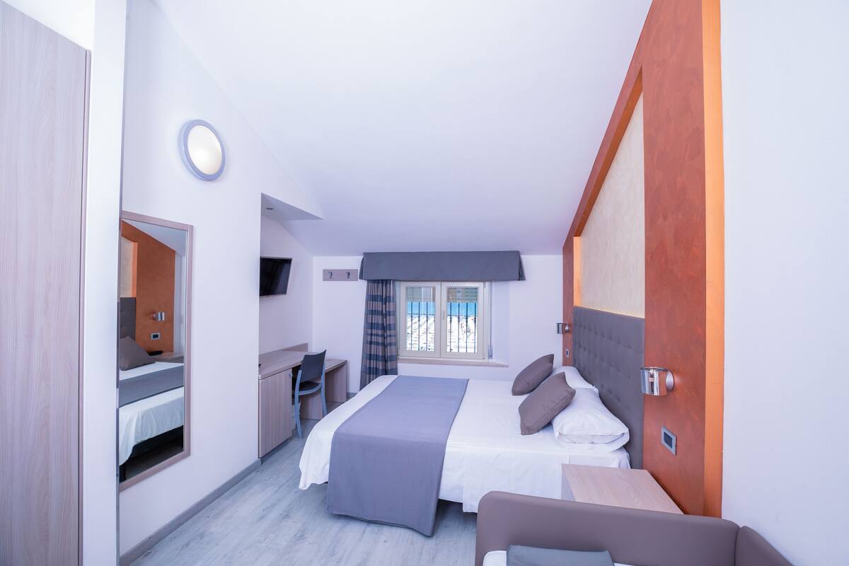 A modern hotel room with a bed, desk, and seating area.