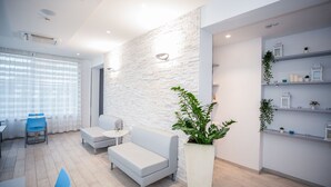 Un intérieur moderne avec un mur en briques blanches, un canapé blanc, une petite table et une plante en pot.
