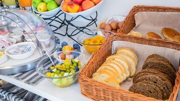 Un bufé de desayuno con diversas frutas, pan y productos lácteos.