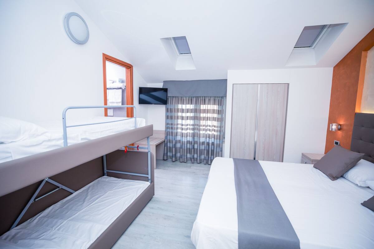 A modern hotel room with bunk beds, a television, a wardrobe, and skylights.