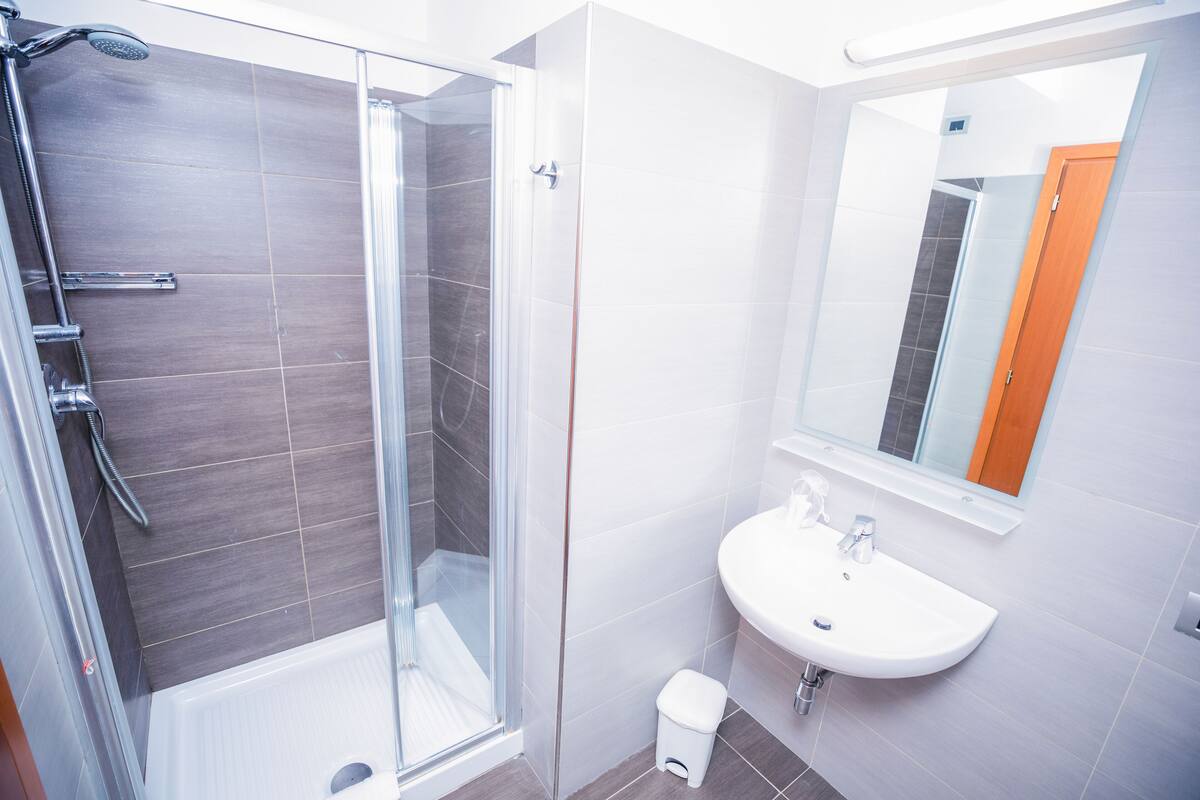 A modern bathroom with a glass-enclosed shower, a white sink, and a mirror above it.