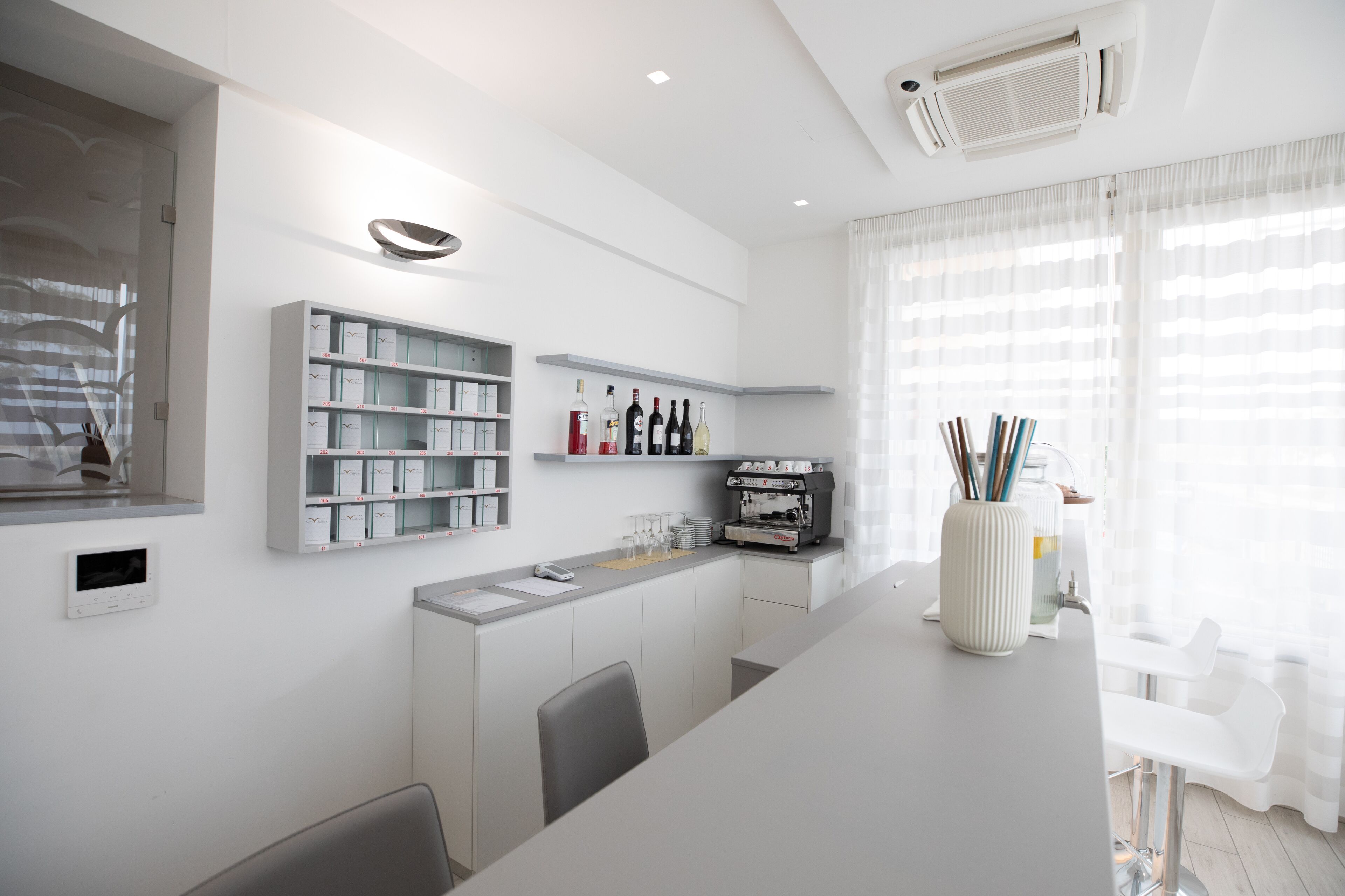 Una cocina moderna con armarios blancos, una máquina de espresso integrada y una vitrina de vidrio.