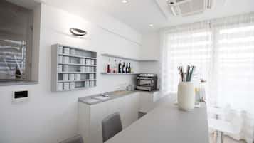 A modern kitchen with white cabinetry, a built-in espresso machine, and a glass display case.