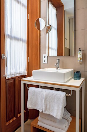 A bathroom with a wooden door, a white sink, a mirror, and a towel rack. - Hotel boutique Párraga Siete (Granada)