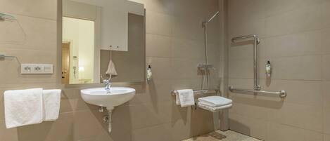 Un baño moderno con lavamanos, espejo y ducha.