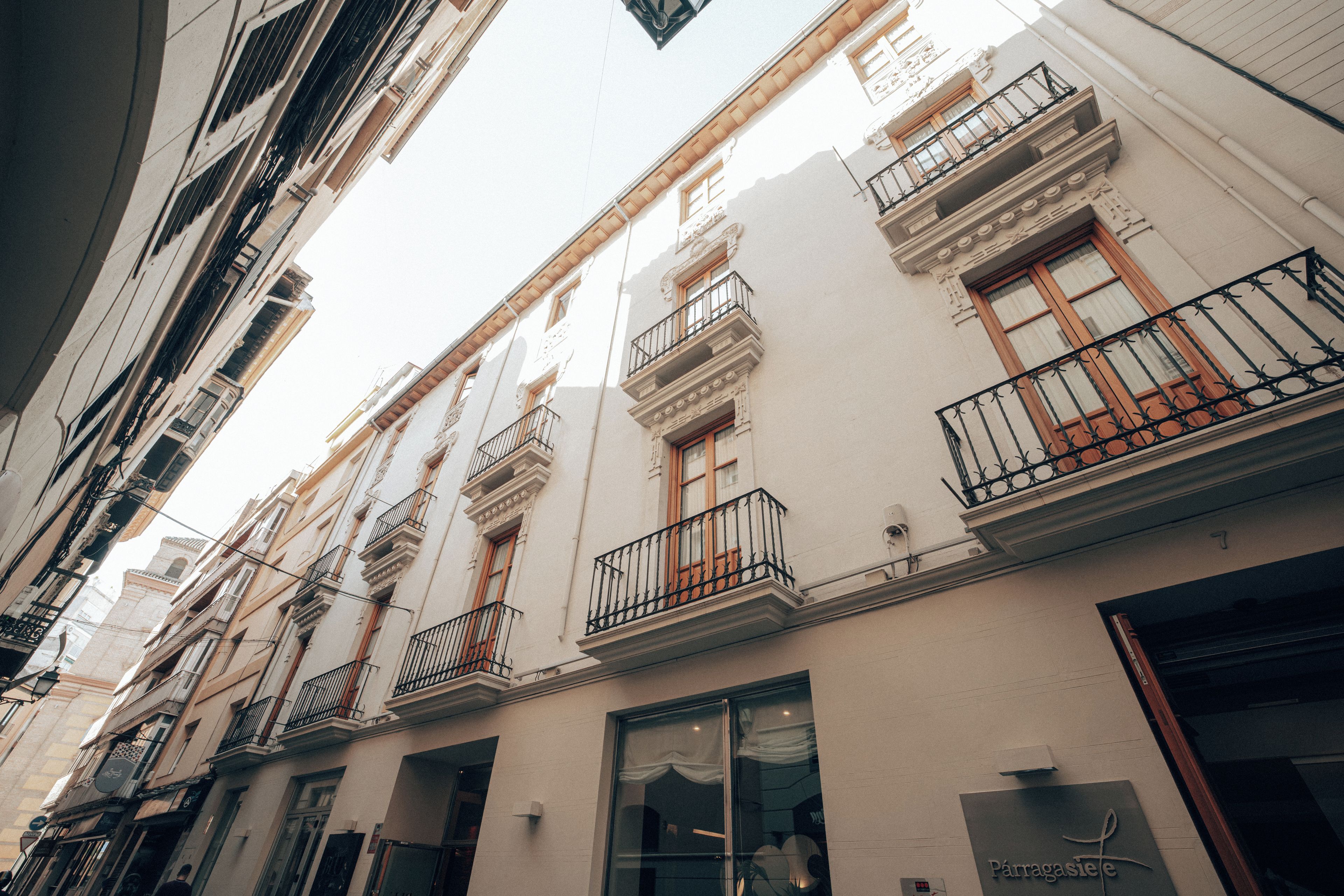 A multi-story building with balconies, large windows, and a sign for 'Páragasie.'