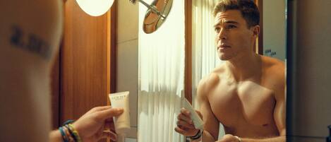 A bathroom with a mirror, a light fixture, and a bottle of lotion.