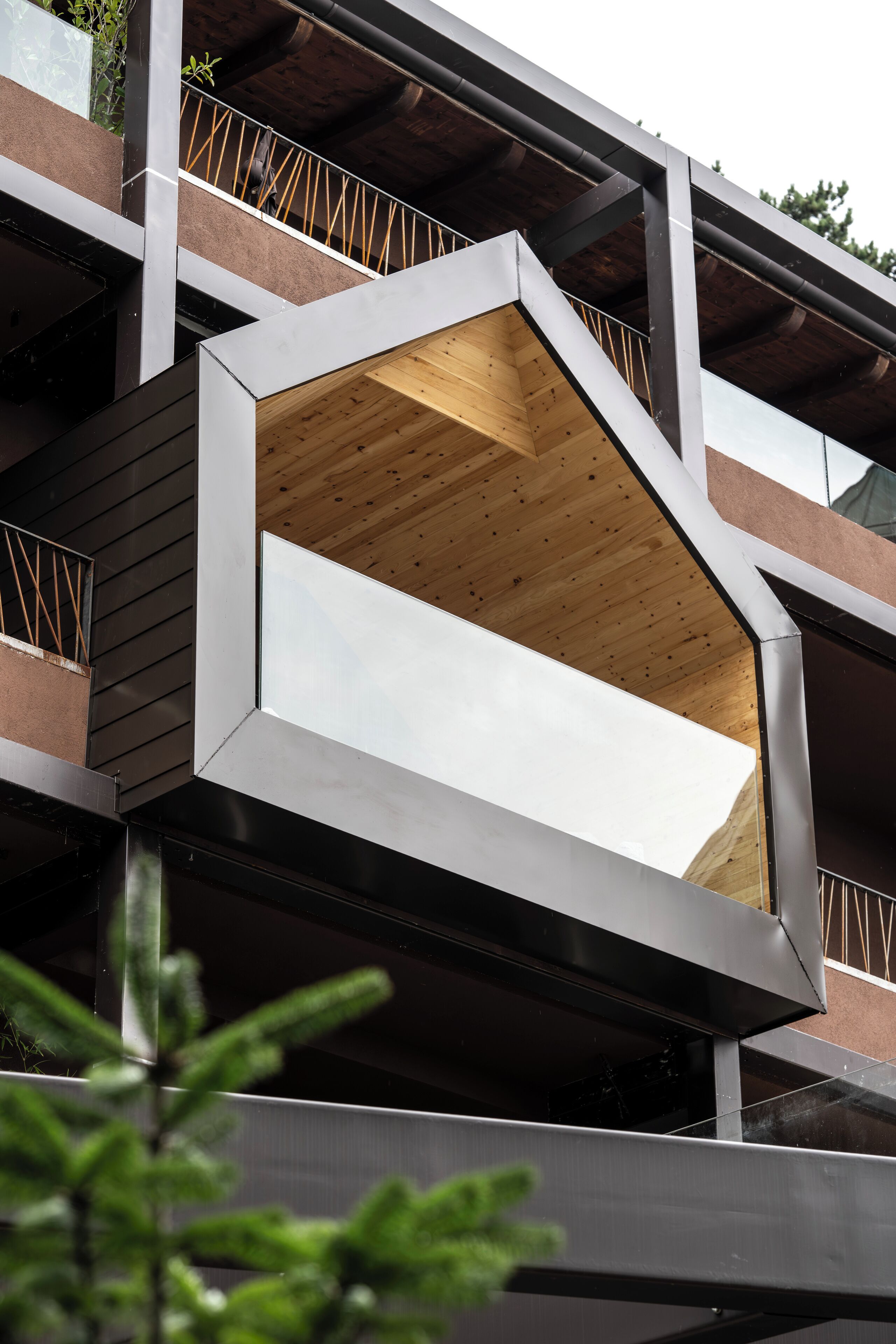 A modern building with a unique geometric balcony design, featuring a combination of metal and wooden materials.